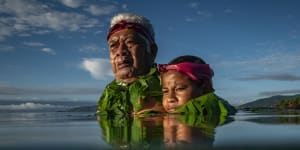 Kioa island resident Lotomau Fiafia and his grandson John. Lotomau was born on the island in 1952 and has seen erosion of the shoreline in the past decades. He stands in the water roughly where the shoreline used to be when he was young.