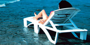 WOMAN LYING ON BEACH CHAIr.