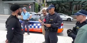 A NSW police officer serves Thomas Sewell (left) with an order prohibiting him from entering the City of Sydney on Australia Day.