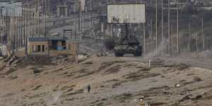 A Palestinian runs away from an Israeli tank in the central Gaza Strip on Sunday.