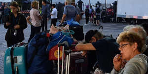 Passengers sit with their luggage after disembarking from the Ruby Princess cruise ship on March 19 at Circular Quay.