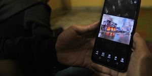 A Myanmar refugee who fled the violence watches photos of it on their phone in India.