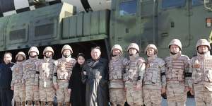 Kim Jong-un (centre) and his daughter pose with soldiers for a photo in front of what it says a Hwasong-17 intercontinental ballistic missile.