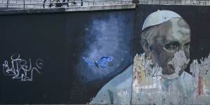 A cyclist pedals his bike up a ramp near a weathered mural of Pope Francis,in Buenos Aires,Argentina,on March 2. 