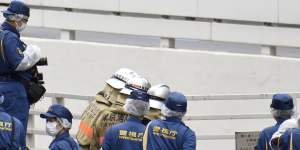 Police and firefighters inspect the scene where a man set himself on fire in Tokyo on Wednesday. 