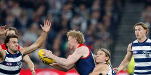 Clayton Oliver of the Demons is tackled by Mark Blicavs of the Cats.