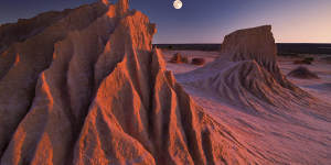 The full moon rises while the sun sets simultaneously at the ancient sandstone Walls of China at Mungo National Park.