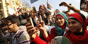 Young Egyptian men and women use their mobile phones to record the celebrations in Egypt's Tahrir Square at the overthrow of President Hosni Mubarak.