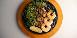 Rice,pitch-black with squid ink,is topped with fat lobes of sweetbread and prawns.