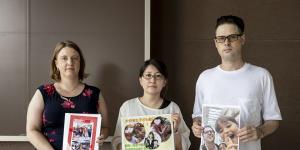 Catherine Henderson,Izumi Dobashi and Scott McIntyre hold photos up of their children. 