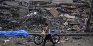 A Palestinian child walks with a bicycle by the rubble of a building after it was hit by an Israeli airstrike,in Gaza City on Sunday