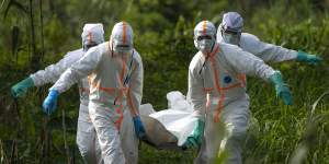 Burial workers in protective gear carry the remains of someone that died of Ebola in Beni,Congo in 2019.