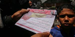 Palestinians read leaflets dropped by Israeli aircraft warning them to evacuate on Monday ahead of military operations in Rafah,Gaza.