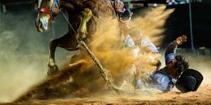 Rider Joe Curtin falls with a bronco horse at a combined rodeo,branding,campdraft and gymkhana weekend in Birdsville. Many competitors travelled for days from isolated cattle stations to try their skills against other jackaroos and jillaroos.