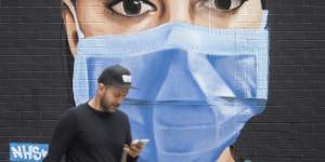 A man passes a mural depicting a nurse wearing scrubs and face mask in the Shoreditch area of east London,following the introduction of measures to bring England out of the coronavirus lockdown,Thursday June 4,2020. 