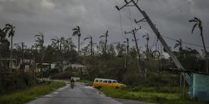 A classic American car drives past utility poles tilted by Hurricane Ian in Pinar del Rio,Cuba.