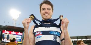 Isaac Smith poses with his 2022 Norm Smith and AFL premiership medals.