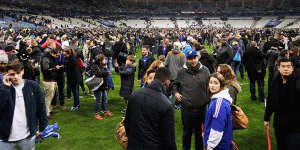 Terrified:Spectators gather on the pitch at Stade de France after news of the bombing and terrorist attacks reached the fans.