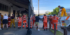 SES and CFA volunteers form a human chain as they help lay sandbags at The Black Pudding Cafe.