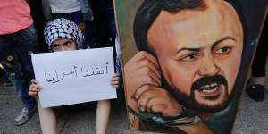 A Palestinian child holds a placard in support of"our prisoners"next to a painting of Marwan Barghouti in the Lebanese capital,Beirut.