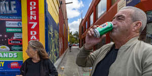 A man and a woman drink and smoke on the streets of Footscray.
