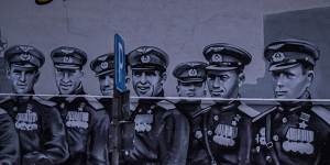 A patriotic mural in Moscow showing Soviet pilots from World War II,based on a photograph of the Victory Parade in 1945. The sign in Russian reads,“The saved world remembers you!”