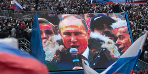 Attendees wave Russian national flags in support of Vladimir Putin,Russia's President,as he speaks on screen during a pre-election rally at Luzhniki stadium in Moscow,Russia in March. 