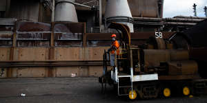 A BlueScope worker sits at the front of one of the company’s “torpedoes”,a wagon that takes 180 tonnes of molten iron per tube from the blast furnace to a steel-processing plant.