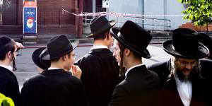 Ultra-orthodox Jewish community members gather outside their burnt synagogue after Friday’s arson attack.