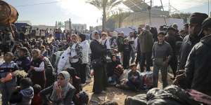 Displaced Palestinians gather with their belongings near a roadblock on the al Rashid Street,as they wait to return to their homes in the northern part of the Gaza Strip on Sunday.