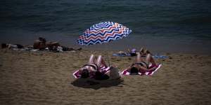 People sunbathe on a beach in Barcelona,Spain.