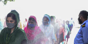 Masked garment workers walk through a disinfection at a factory in Savar,Bangladesh.
