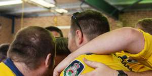 Members of the Horsley Park Rural Fire Brigade embrace while remembering their fallen comrades on Sunday. 