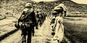 US soldiers file past Korean women and children carrying their possessions in 1950. 
