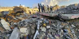 Palestinians stand by the rubble of a building destroyed in Israeli airstrikes in Deir el-Balah Gaza Strip on Sunday.