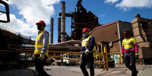 BlueScope employees (from left) Chris Page,Michael Reay,and Craig Nealon walk past part of the blast furnace operating at Port Kembla.