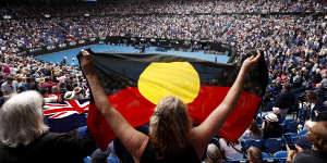 A spectator holds up the Indigenous flag as Ash Barty wins her third-round match at the Australian Open in January.
