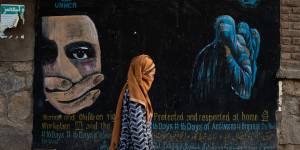 A woman walks past a mural calling for women and children’s rights in Bamian,Afghanistan.