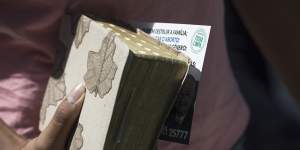 A woman holds her Bible,and an electoral leaflet promoting two candidates that was distributed at the Assembly of God Victory in Christ Church in Rio de Janeiro,Brazil.