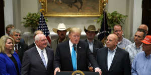 Trump talks about the trade war,flanked by farmers and ranchers,including one whose cap is emblazoned with Make Potatoes Great Again.