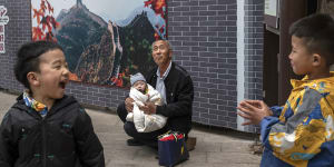 A man holds a baby near other relatives at the Great Wall of China. The state wants families to have more children.