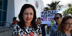 Queensland Premier Annastacia Palaszczuk walks past an anti-Adani coal mine protester as she leaves the Cairns Aquarium on Wednesday.