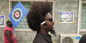 A man plants a Bougainville flag in his hair as he queues up to vote on the opening day of the territory's independence referendum.