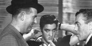 Colonel Parker (left) talks with TV host Ed Sullivan,while Elvis grooms himself backstage at Sullivan’s television show in October 1956.