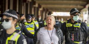 A woman is arrested at Queen Victoria Market on Saturday afternoon after an anti-vaccine protest. 