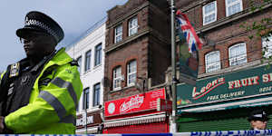Police officers stand in the area where two people were stabbed in Golders Green.