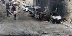 Syrian citizens gathered near burned cars after airstrikes hit Manbij,in Aleppo province,Syria.