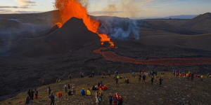 People watch as lava flows from an eruption from the Fagradalsfjall volcano on the Reykjanes Peninsula in southwestern Iceland in May,2021. 