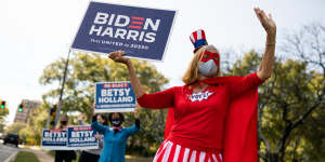 A person dressed in a'Vote'superhero costume holds a campaign sign for Joe Biden outside a polling station in Atlanta,Georgia,on election day.