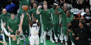 Dallas guard Kyrie Irving shoots for a three-pointer under intense scrutiny from the Celtics bench.